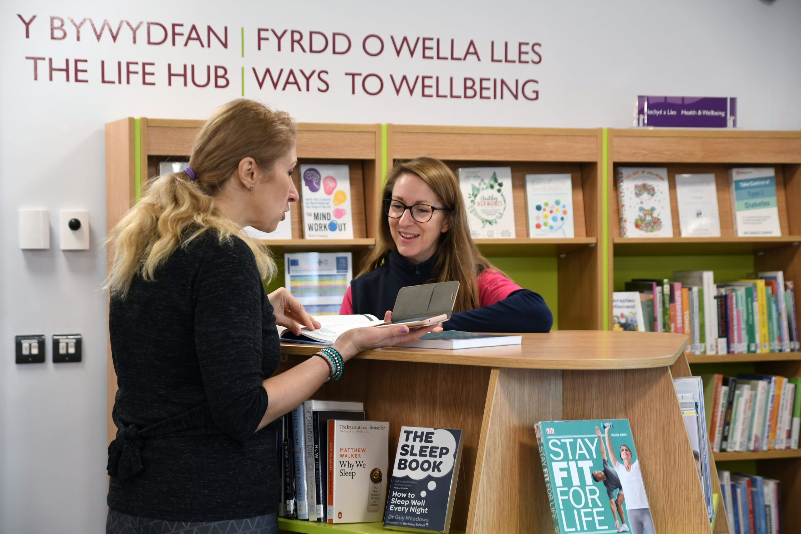 Library users looking at Reading Well collection at Riverside Library Haverfordwest