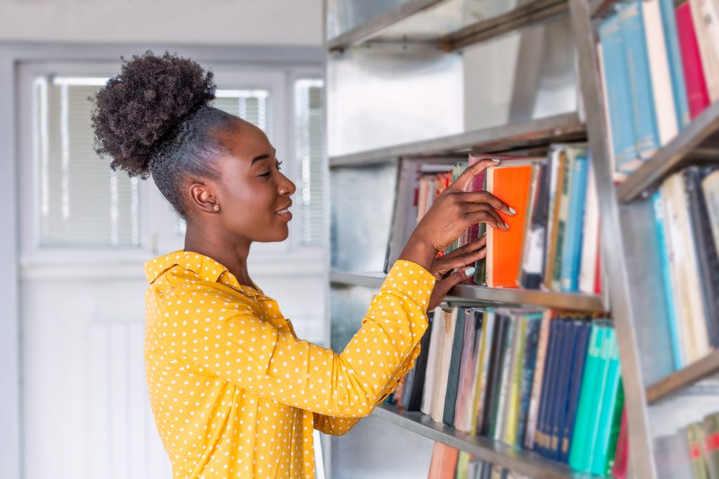 Lady reaching for a book from a bookshelf